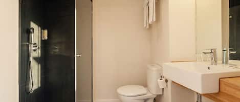 A modern bathroom with a glass shower enclosure, a white toilet, and a sink with a mirror.