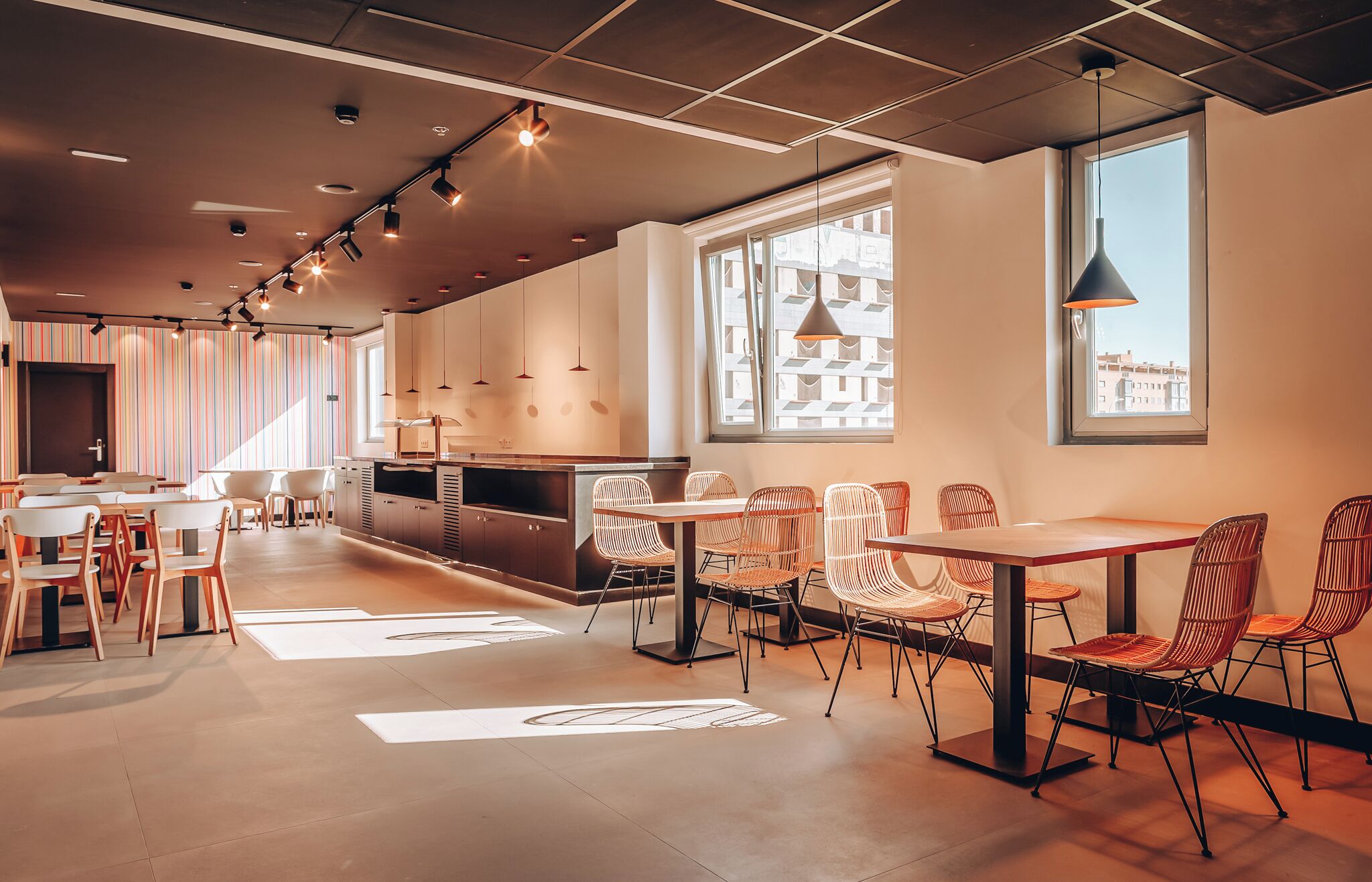 Um restaurante moderno com balcão extenso, cadeiras de vime e iluminação pendente.