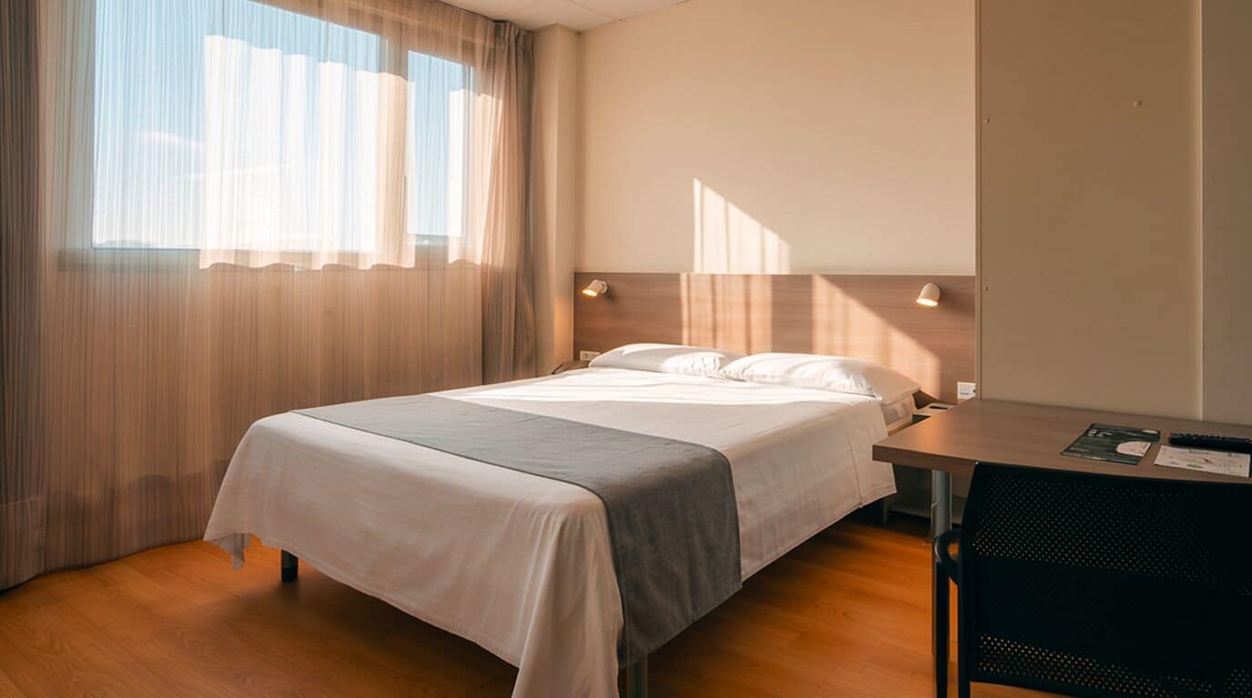 A hotel room with a bed, a desk, and a chair.