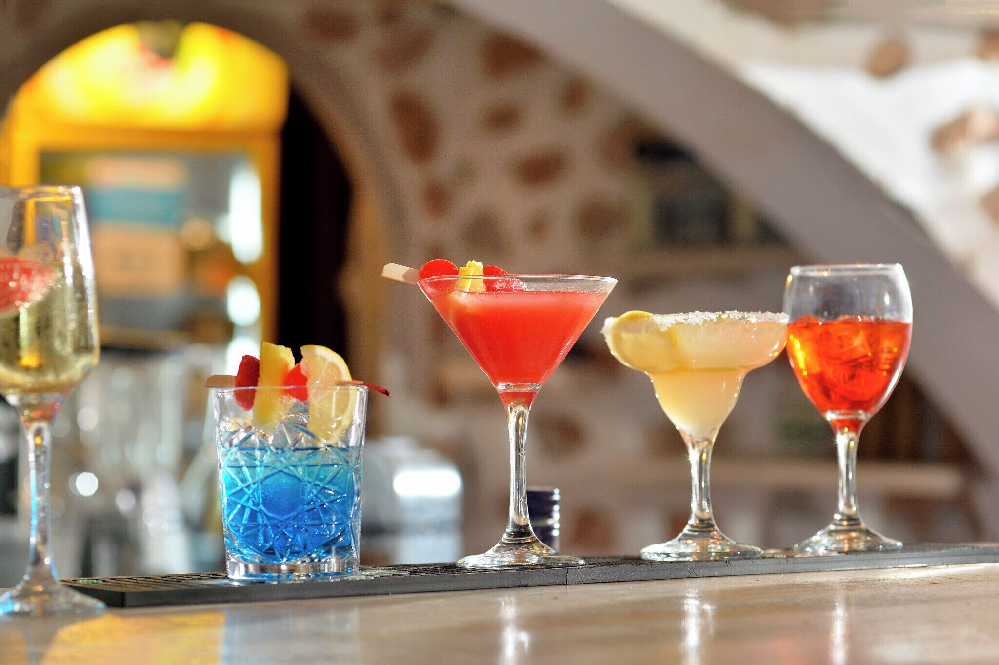 Un bar con cuatro cócteles distintos, cada uno en un vaso original.