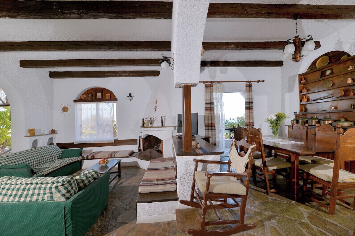 Un interior rústico con chimenea de piedra, muebles de madera y un comedor.