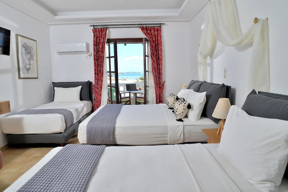 Habitación de hotel con dos camas, un escritorio y vista al mar.