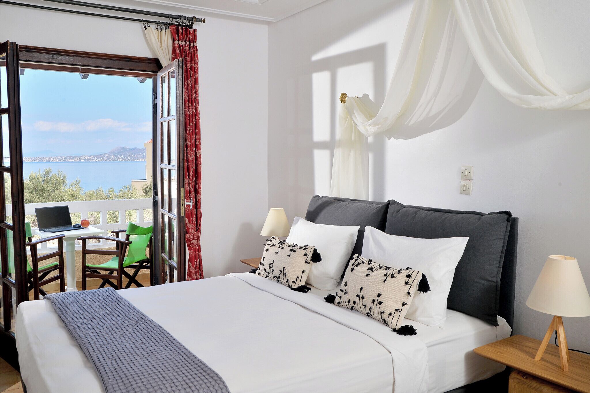 Un dormitorio con cama, un escritorio con computadora portátil, una silla y vista al mar.