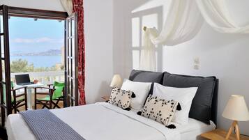 Un dormitorio con cama, un escritorio con computadora portátil, una silla y vista al mar.