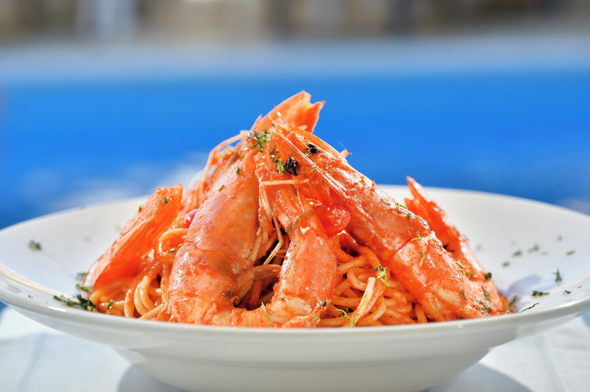 A plate of cooked shrimp with herbs, served on a white plate.
