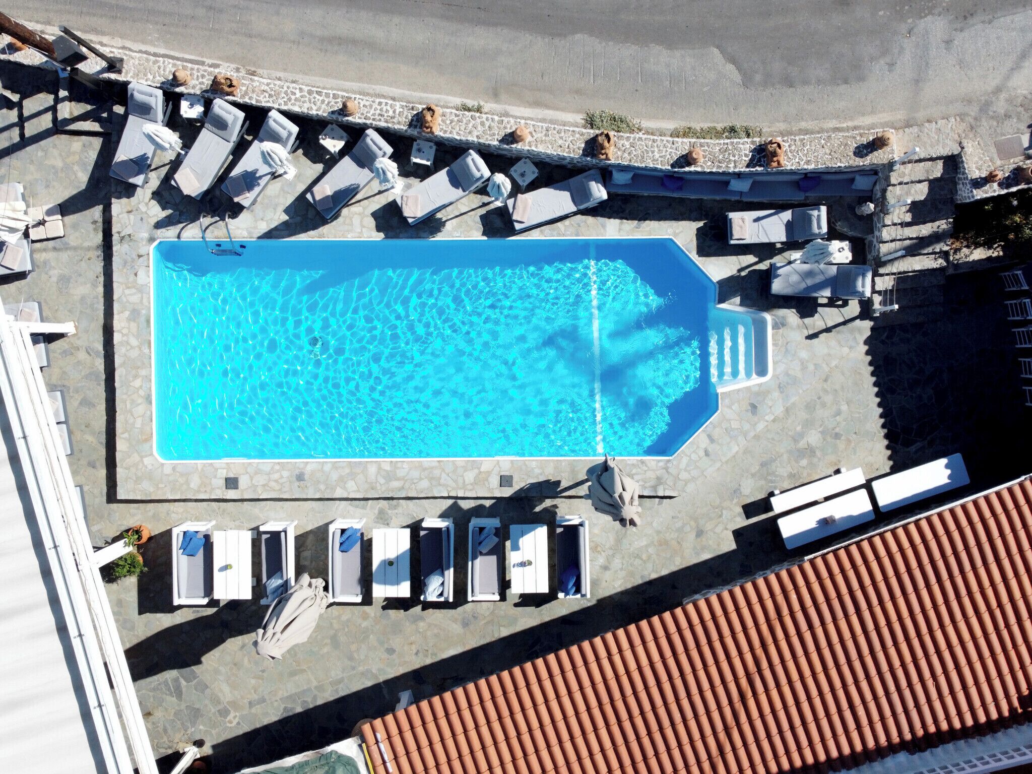 An aerial view of a swimming pool with lounge chairs and umbrellas arranged around it.