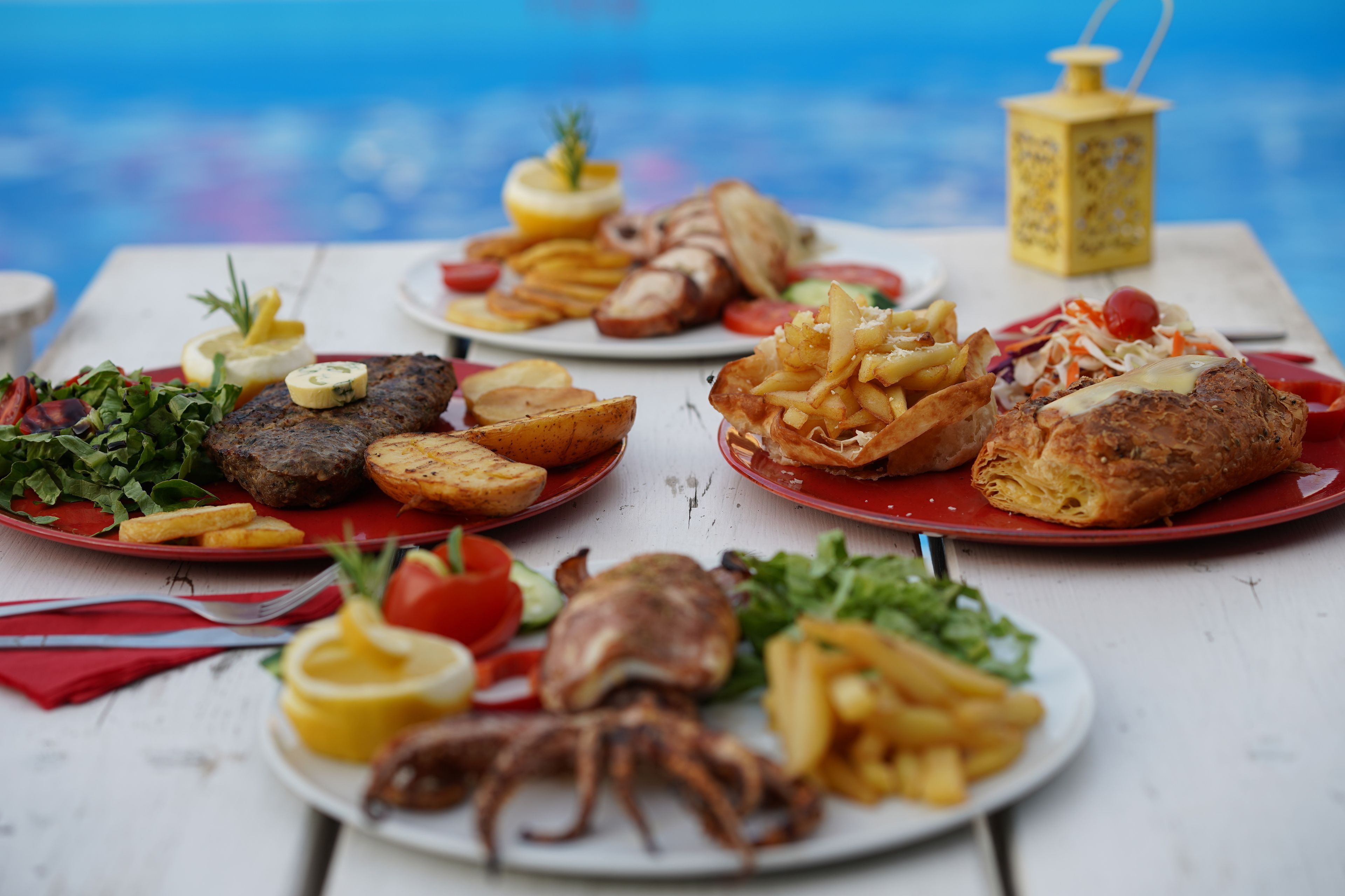 Una mesa con diversos platos, incluyendo carne a la parrilla, mariscos y verduras.