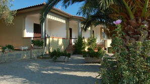 A house with a tiled roof, a porch, and a gravel driveway. - Casa Luppoli (Portoferraio)