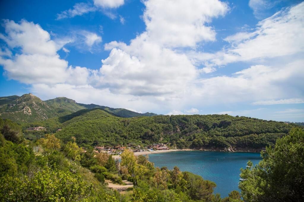 A coastal landscape with a clear sky, a beach, and a mountain range.