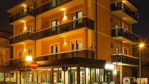 A multi-story hotel with balconies, a ground-level entrance, and a visible sign indicating a pedestrian area. - Hotel Ostuni (Rimini)
