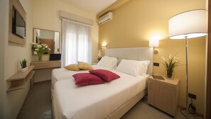 A hotel room with a bed, bedside tables, a desk, a mirror, and a lamp. - Hotel Ostuni (Rimini)