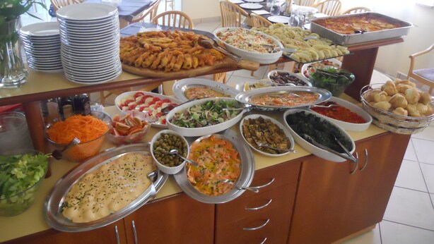 A buffet with various dishes and a dining area with chairs and tables. - Hotel Ostuni (Rimini)