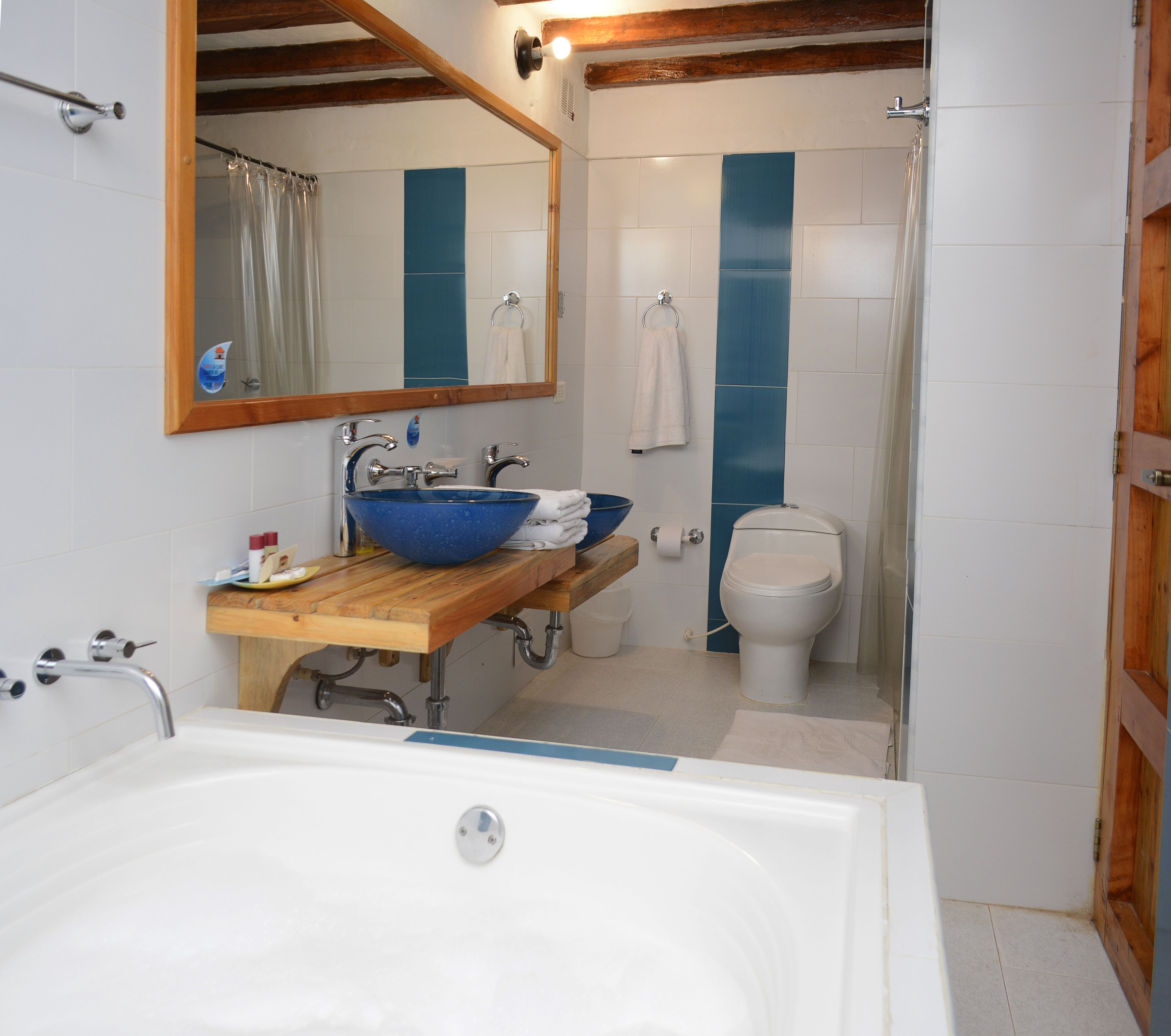 Un baño con bañera, lavabo de color azul, inodoro y zona de ducha.