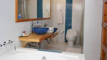 Un baño con bañera, lavabo de color azul, inodoro y zona de ducha.