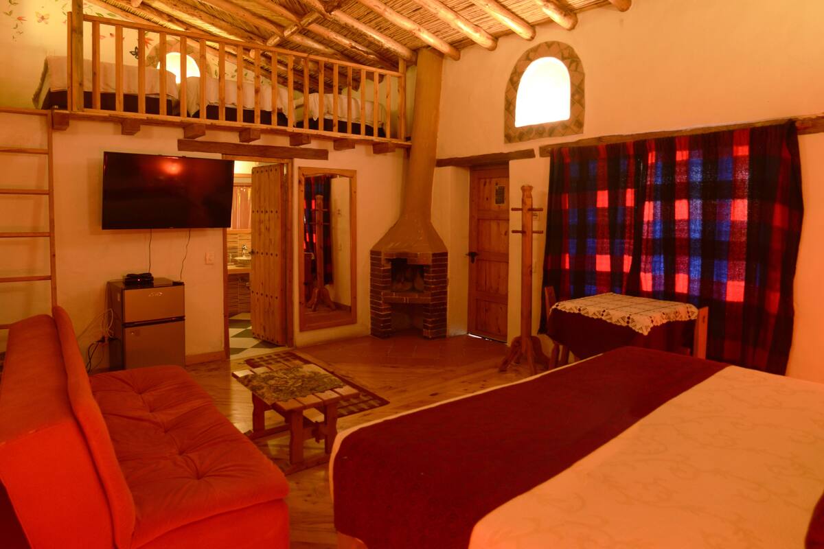 A cozy room with a loft bed, a fireplace, a television, and a dining area.