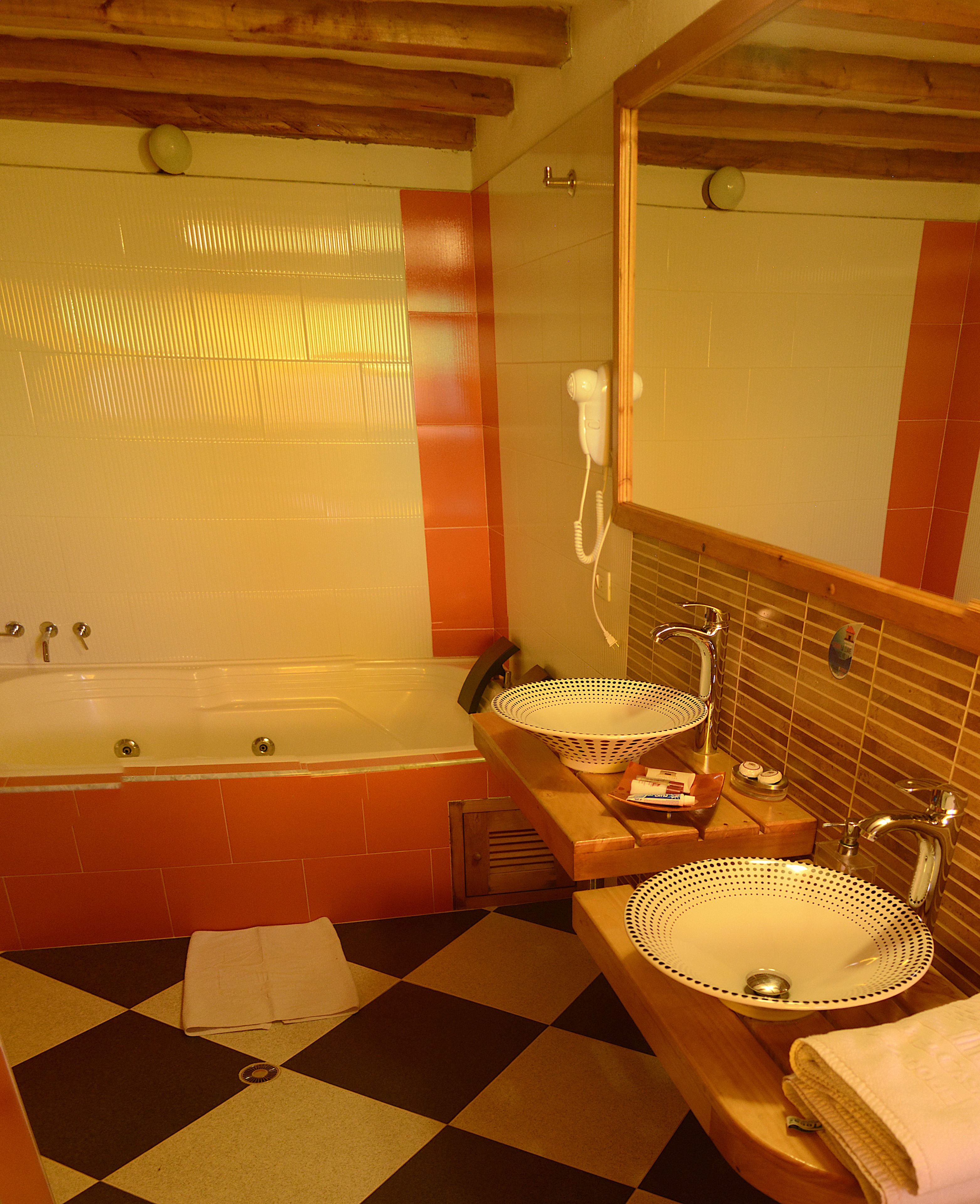 A bathroom with a checkered floor, two sinks with decorative bowls, a hairdryer, and a bathtub.