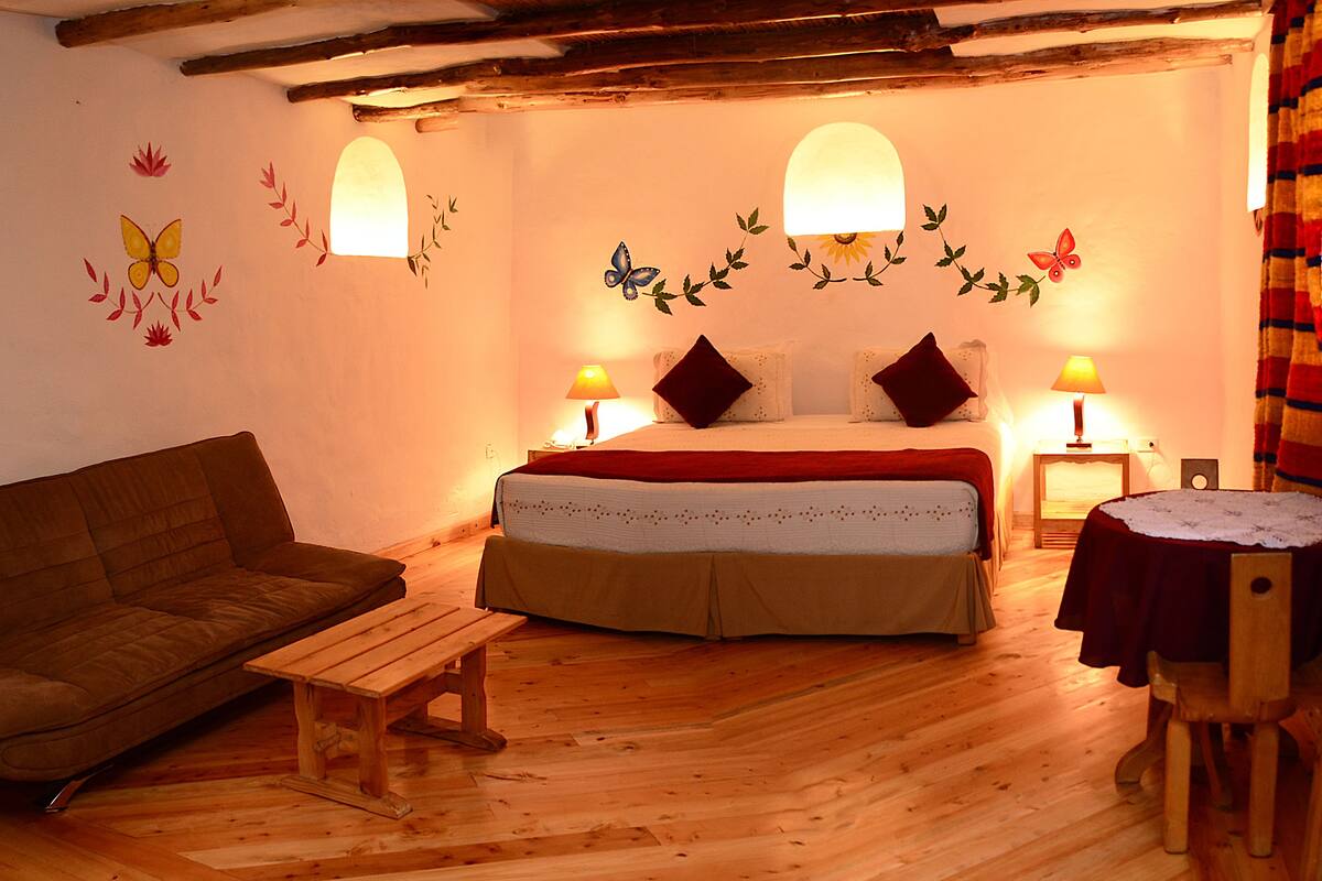 A cozy room with a bed, a wooden bench, a sofa, and a small table.