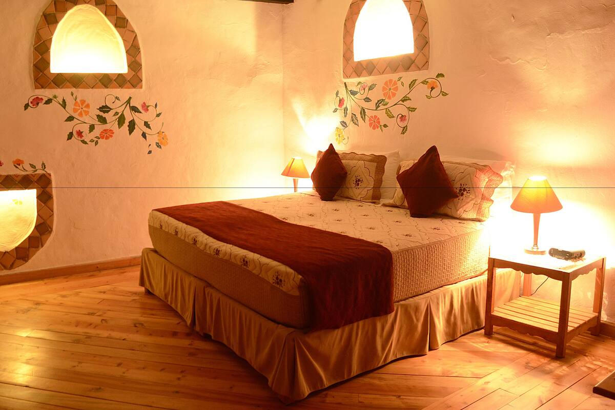 A bedroom with a bed, bedside tables, a TV, and decorative wall lights.