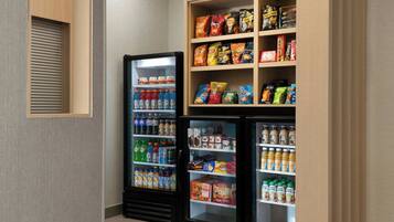 A corner with two beverage refrigerators stocked with various drinks and snacks.