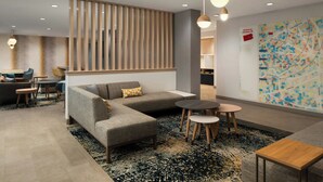 Un vestíbulo moderno con un sofá modular, mesas redondas y un mapa en la pared.