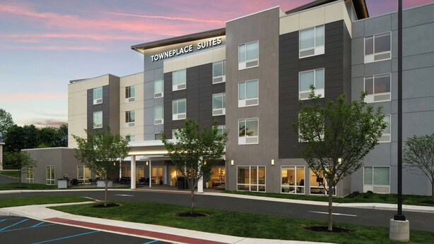 Un hotel moderno con techo plano, múltiples ventanas y un cartel que dice "TOWNEPLACE SUITES".