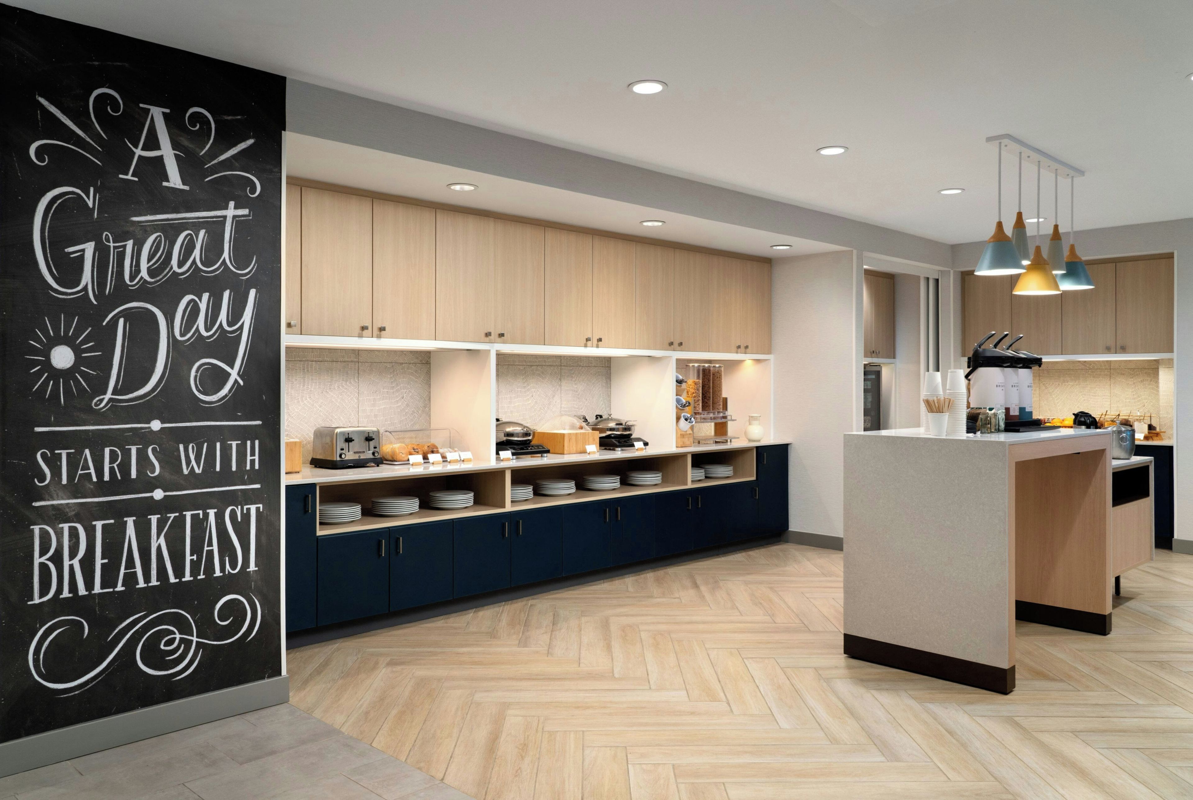 Une cuisine moderne avec des meubles en bois, un bar pour prendre le petit-déjeuner et des luminaires suspendus.