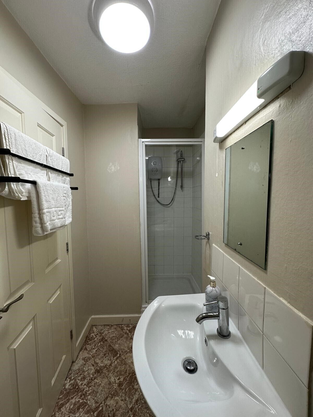 A bathroom with a white sink, a mirror, and a shower.
