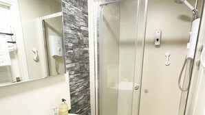 A modern bathroom with a white sink, a glass-enclosed shower, and a mirror above the sink.