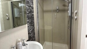 A modern bathroom with a glass-enclosed shower, a white sink, and a marble countertop.