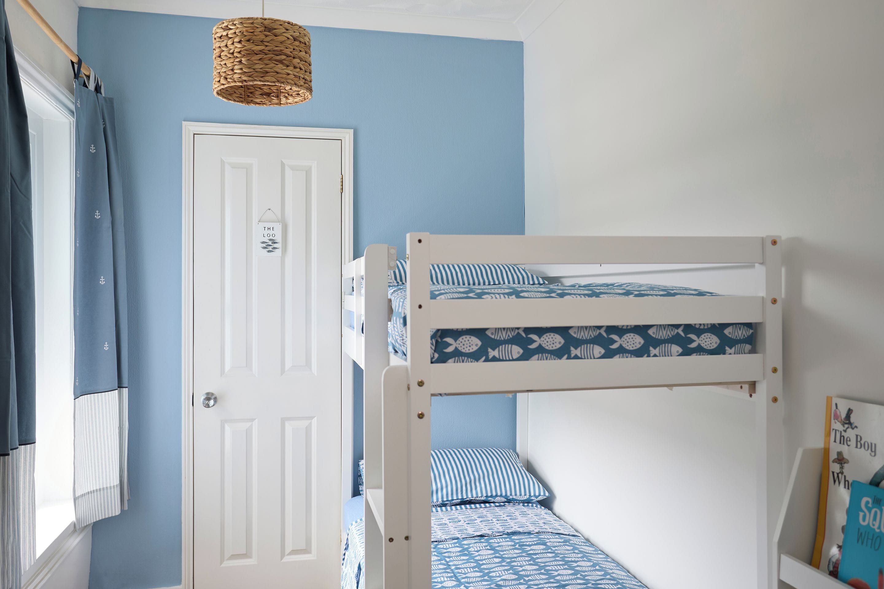A room with a bunk bed, a white door, and a hanging light fixture.