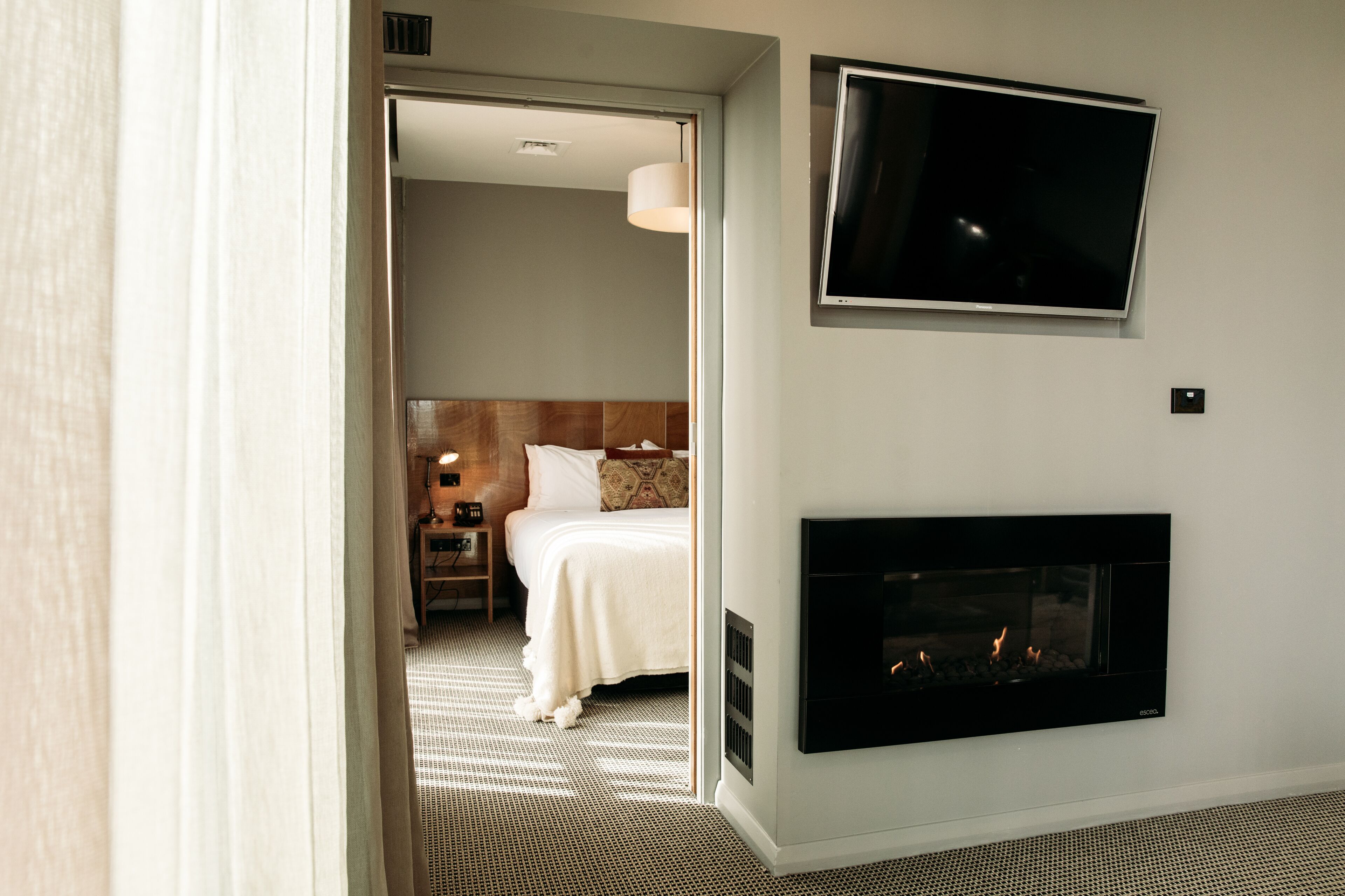 Una habitación de hotel con cama, televisión y chimenea.