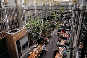 An indoor dining area with wooden tables and chairs, a pizza stand, and hanging plants.