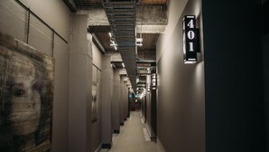 Un pasillo con un cartel con el número '401', indicando un número de habitación. El pasillo tiene un techo de concreto con vigas y tuberías a la vista.