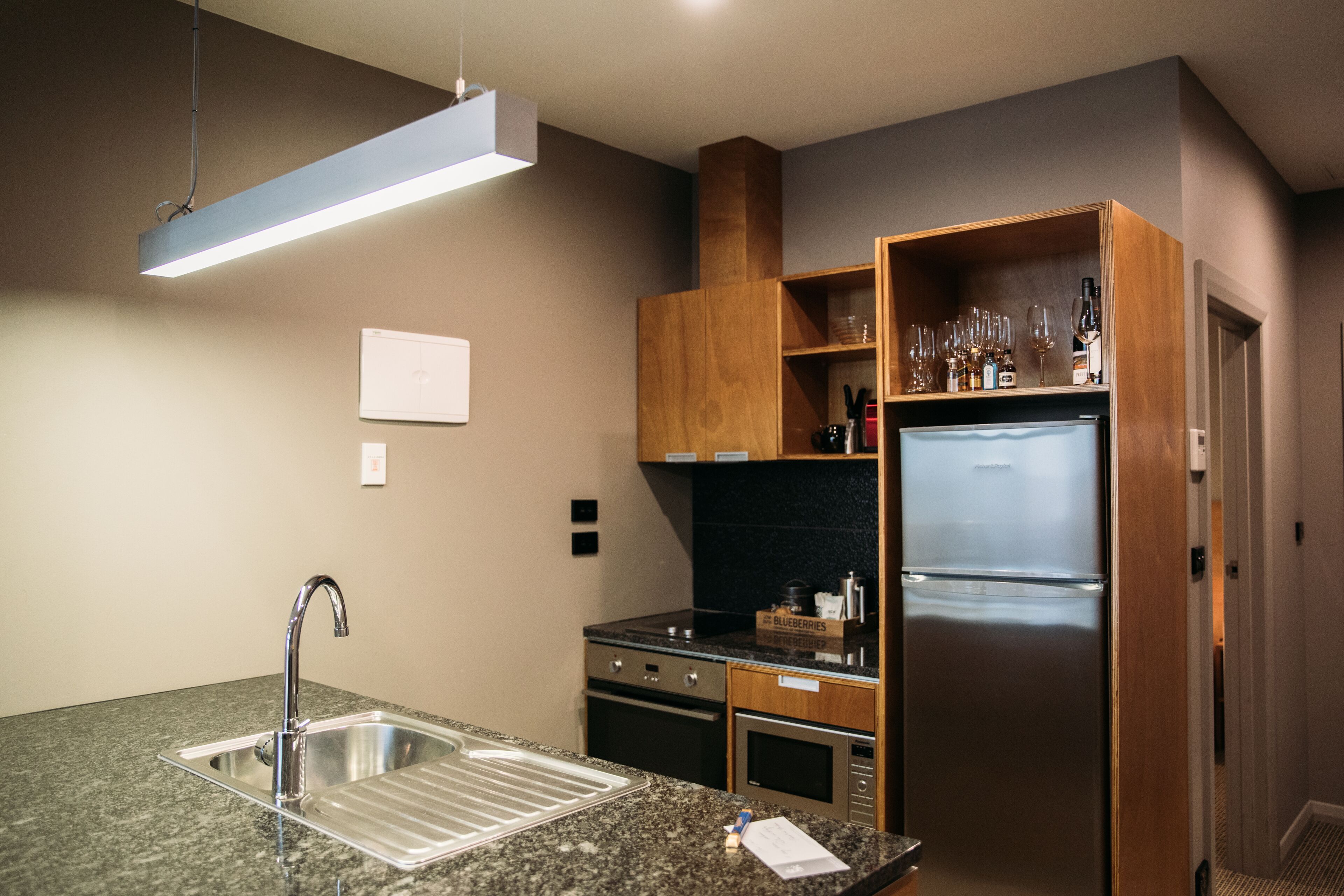 Una cocina moderna con un refrigerador de acero inoxidable, encimera de granito y gabinetes de madera.