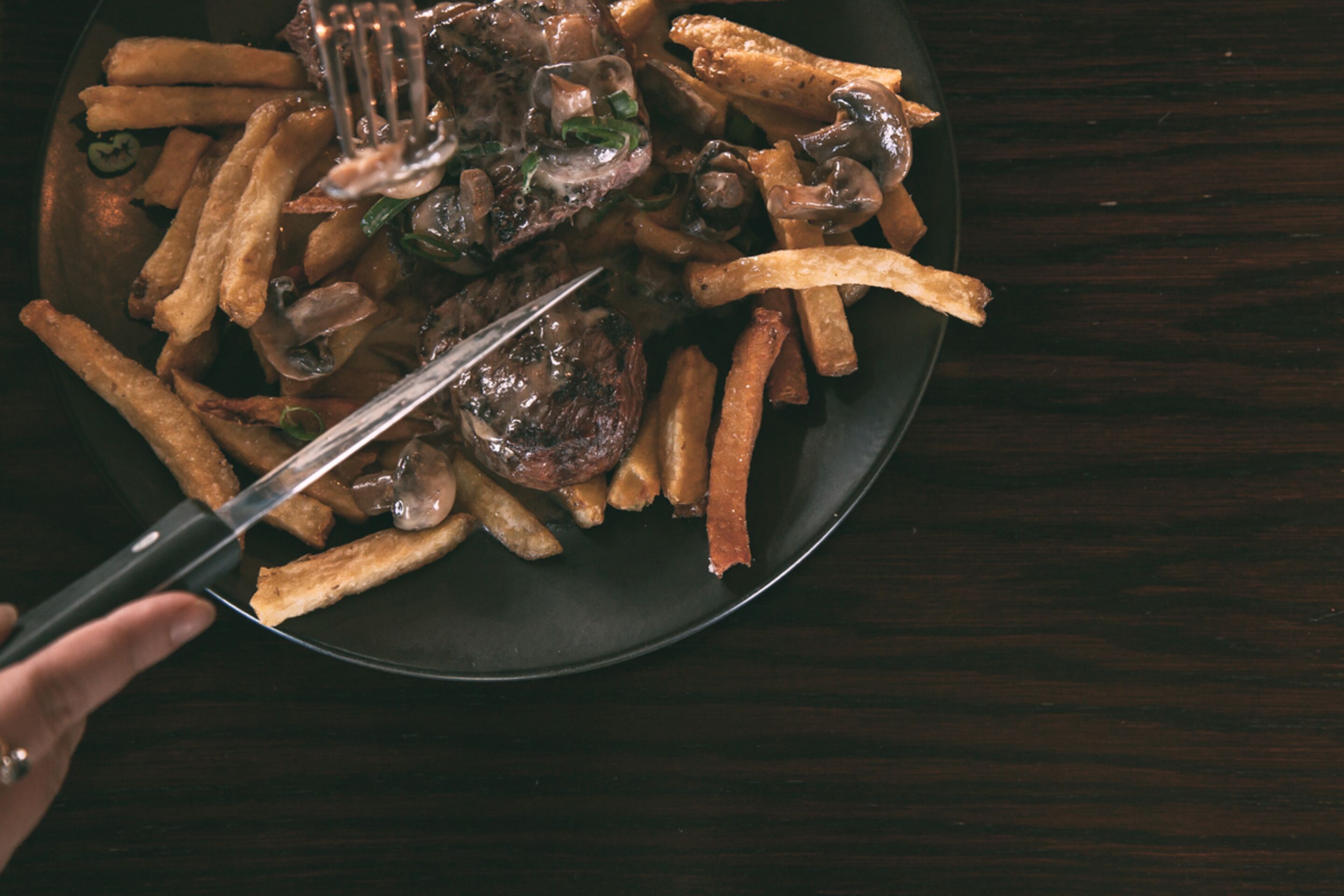 Un plato de comida con papas fritas y champiñones, servido con un tenedor.