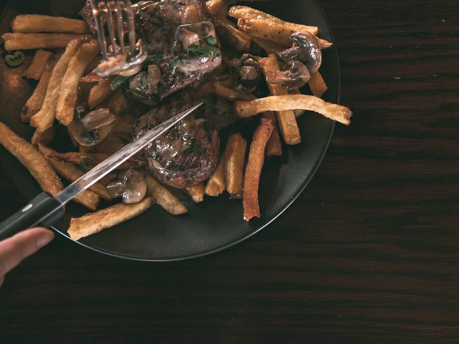 Un plato de comida con papas fritas y champiñones, servido con un tenedor.