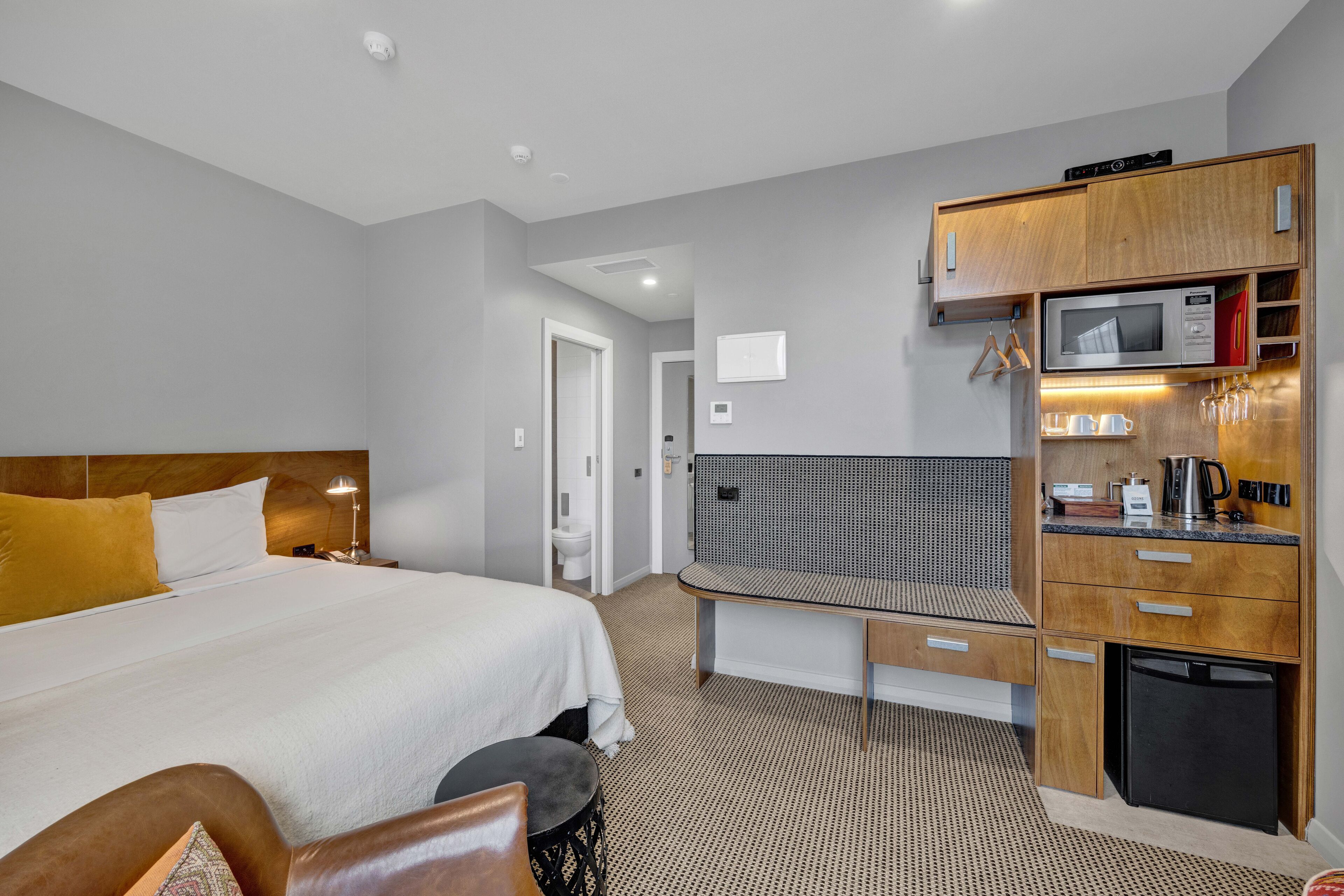 A hotel room with a large bed, a small desk, a microwave, and a refrigerator.