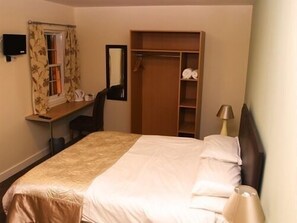 A hotel room with a bed, a desk with a chair, a wardrobe, and a mirror. - The Downe Arms (Goole)