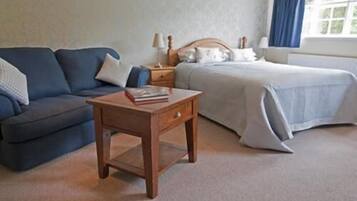 A bedroom with a bed, a sofa, a nightstand, and a small table with a book.