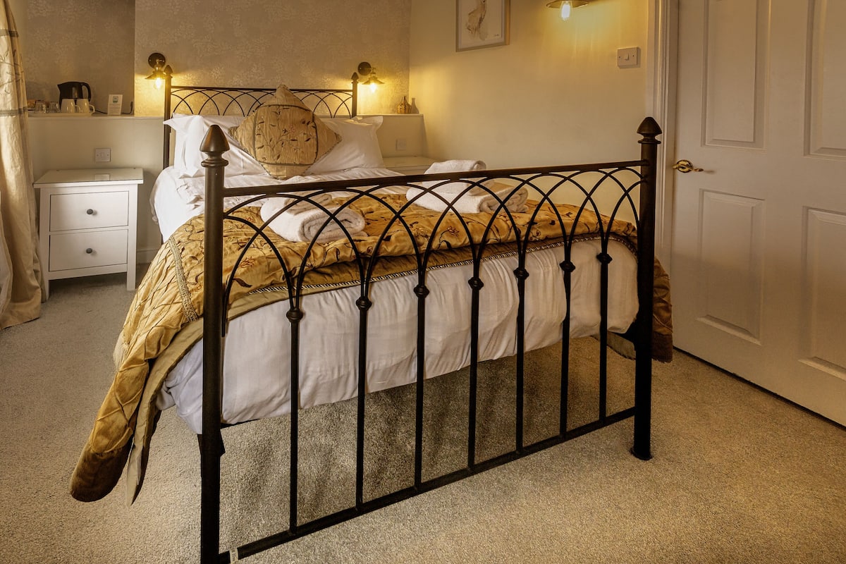 A bedroom with a metal bed frame, a bedside table, a nightstand, and a door.
