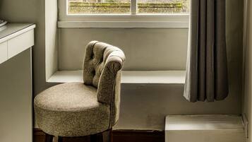 Une pièce d’angle avec une fenêtre, une chaise et un radiateur.