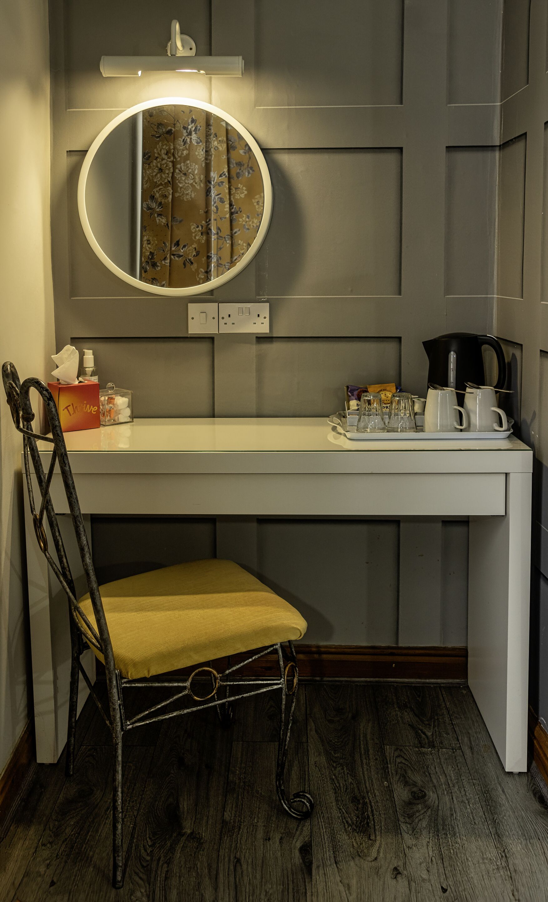 A compact, modern bathroom with a vanity, a round mirror, and a chair.