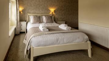 A neatly made bed with a headboard, two bedside tables, and wall-mounted lamps.