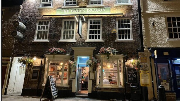 The Green Dragon pub with a traditional stone facade, two entrance arches adorned with flowers, and a signboard indicating food and drink services. - The Green Dragon at Bedale by OYO (Bedale)
