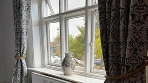 Ein Schlafzimmer mit Fenster, Heizkörper und einer Vase auf der Fensterbank.