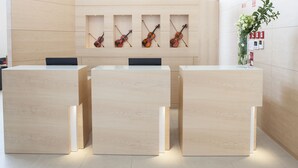 A reception desk with three wooden panels, a wall-mounted violin display, and a potted plant. - Hotel da Música (Porto)