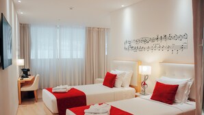 A hotel room with two beds, a desk, and a wall with musical notes. - Hotel da Música (Porto)
