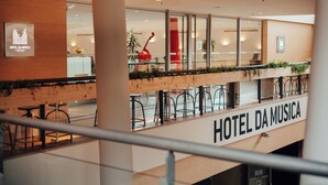 A modern hotel interior with a balcony, seating area, and a sign reading 'HOTEL DA MUSICA'. - Hotel da Música (Porto)