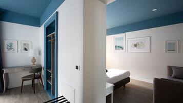 A modern bedroom with a desk, chair, bed, and artwork on the walls.