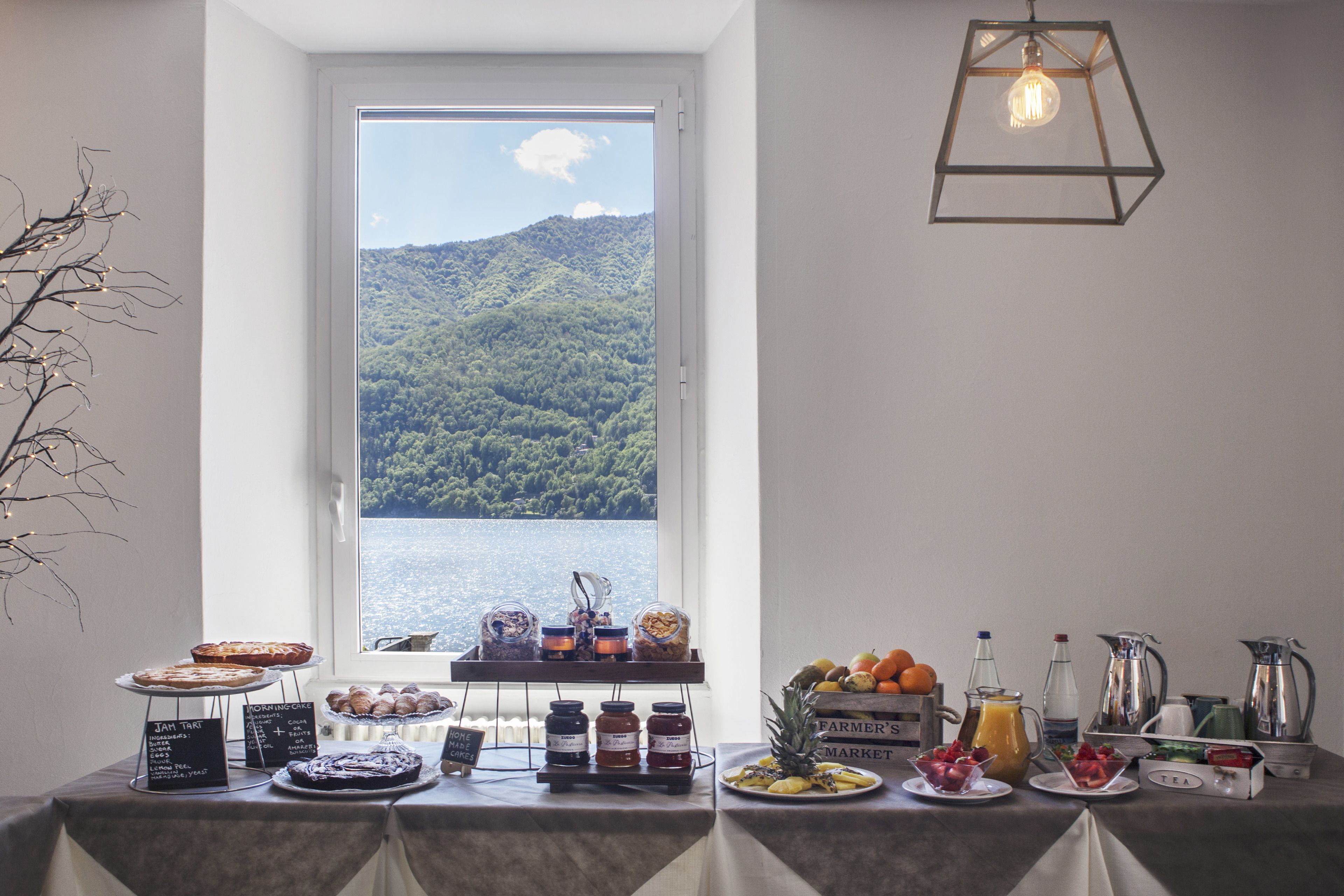 A breakfast buffet with various food items and a view of a lake and mountains.